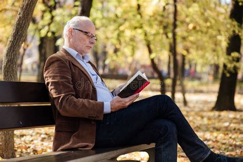 Anziano che legge un libro con espressione pensierosa