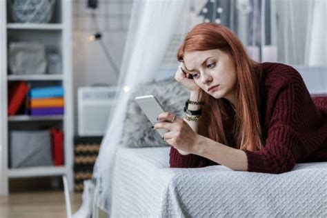 Adolescente che guarda il telefono con preoccupazione