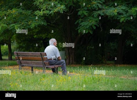 Anziano pensieroso seduto su una panchina al parco