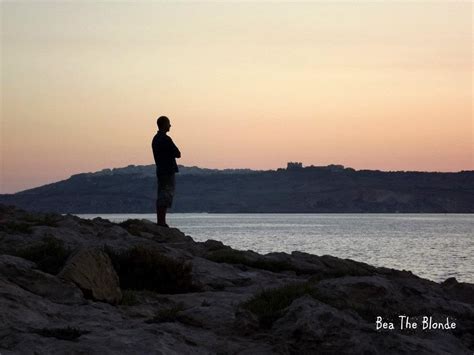 Uomo seduto su una scogliera che osserva il mare al tramonto