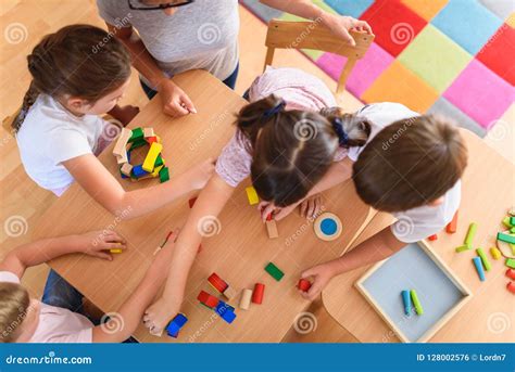 Bambini che giocano insieme con un insegnante che li osserva con attenzione