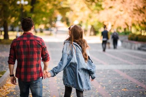 Una coppia che cammina tenendosi per mano in un parco