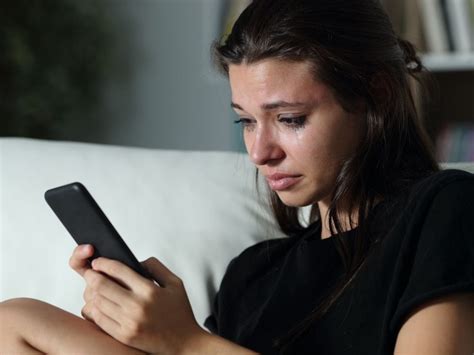 persona che piange guardando il telefono