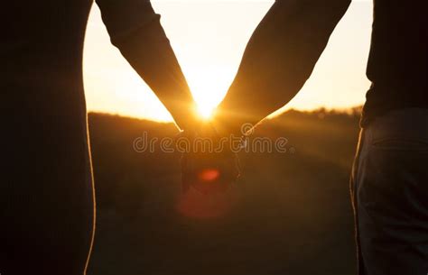 coppia che si tiene per mano guardando un tramonto