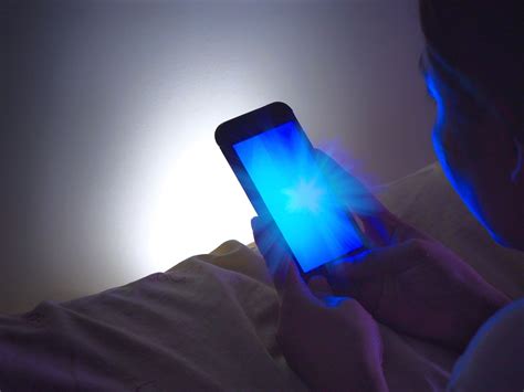 Persona che guarda il telefono a letto, luce blu dello schermo