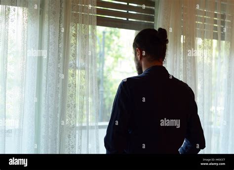 Persona che guarda fuori dalla finestra con espressione preoccupata