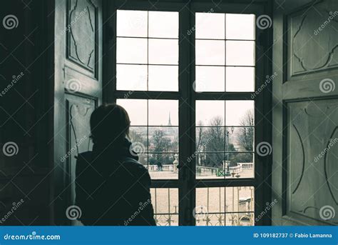 donna che guarda attraverso una finestra un paesaggio urbano