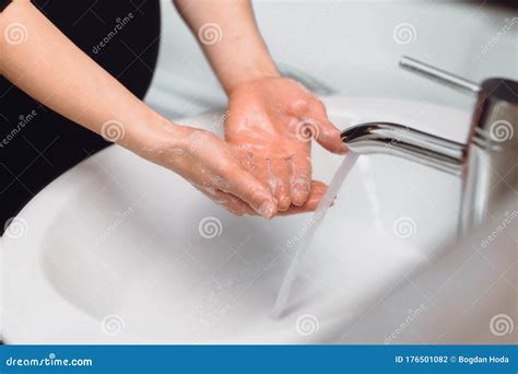 Persona che osserva le mani sotto il rubinetto